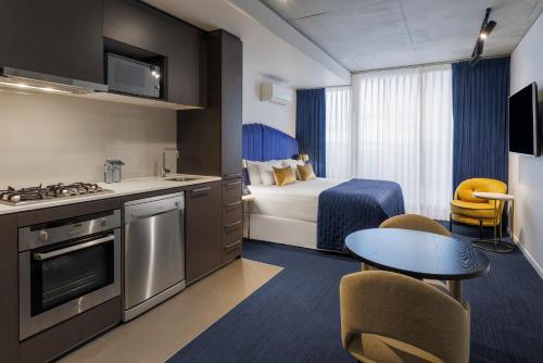 a hotel room with a kitchen and a bed and a table at Avani Melbourne Jazz Corner Residences in Melbourne