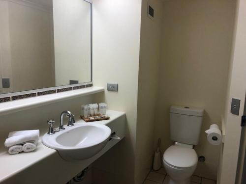 City Oasis Inn في تاونزفيل: حمام مع حوض ومرحاض ومرآة