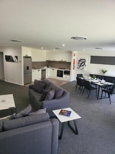 uma sala de estar com sofás e uma mesa e uma cozinha em CH Boutique Apartments The Ringers Road em Tamworth