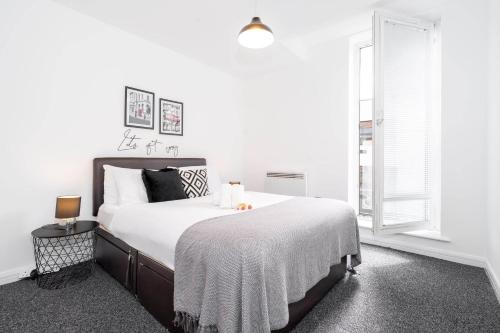 ein Schlafzimmer mit einem großen Bett mit weißer Bettwäsche und einem Fenster in der Unterkunft Vibrant 1 Bedroom Cosy Apartment - City Centre in Birmingham