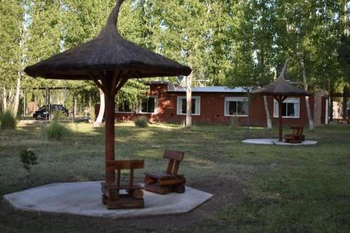 an umbrella and benches in a yard with a house at Cabañas El Labriego in Malargüe