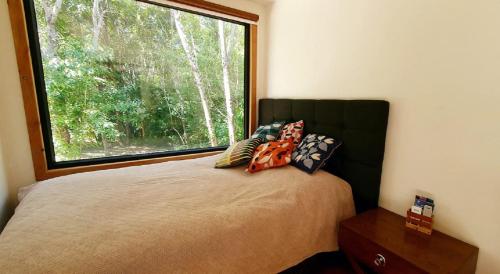 um quarto com uma cama e uma janela grande em Cabañas Vista Bonita em Pucón