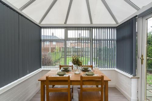 um jardim de Inverno com uma mesa e cadeiras de madeira em Stylish two bedroom home SHEFFIELD em Sheffield