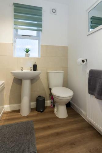 a bathroom with a toilet and a sink and a window at Stylish two bedroom home SHEFFIELD in Sheffield