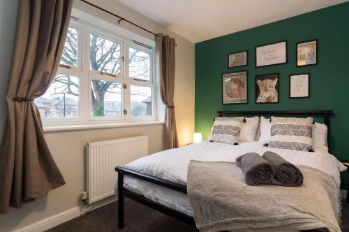 a bedroom with a bed with green walls and a window at Stylish two bedroom home SHEFFIELD in Sheffield