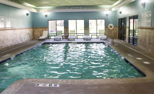 ein Swimmingpool mit Stühlen in einem Gebäude in der Unterkunft Holiday Inn Express Cedar Rapids - Collins Road by IHG in Cedar Rapids