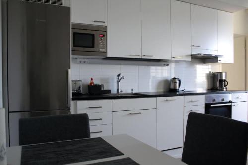 a kitchen with white appliances and white cabinets at Modern apartment with Sauna, near Transit Hub/Dixi in Vantaa