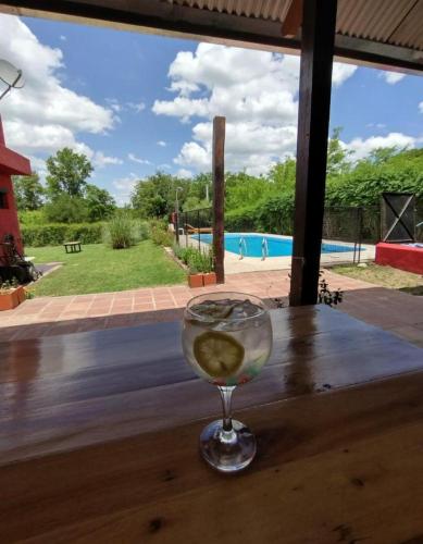una copa de vino en una mesa con una piscina en Casita de las sierras en Córdoba