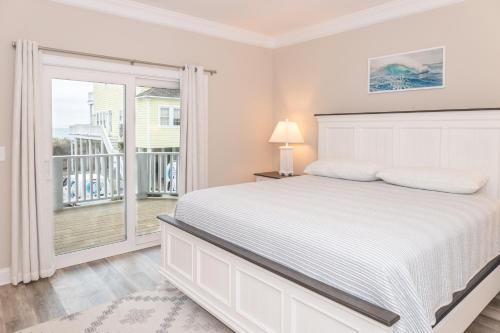 een witte slaapkamer met een bed en een balkon bij Villas View in North Topsail Beach