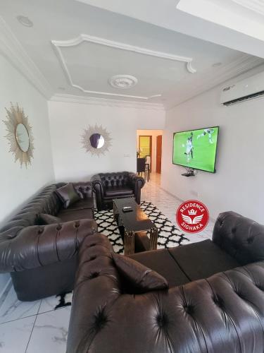 a living room with leather furniture and a flat screen tv at Résidence Sighaka - Suite Royale - WiFi, Gardien, Parking in Douala