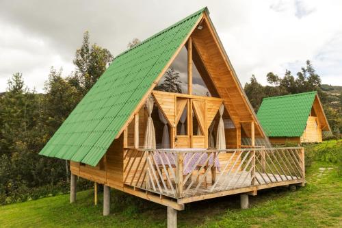 une maison en bois avec un toit vert dans l'établissement Glamping las 4 estaciones, à Guatavita