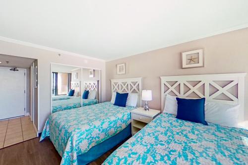 two beds in a hotel room with blue and white sheets at Caravelle Resort #622 in Myrtle Beach