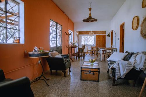 sala de estar con paredes de color naranja, mesa y sillas en Inti, hospedaje de campo. en Arrecifes