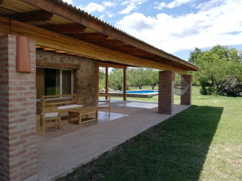 a pavilion with a table and a bench on a patio at Casa de Montaña in Yacanto