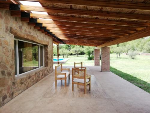 a patio with two chairs and a wooden ceiling at Casa de Montaña in Yacanto