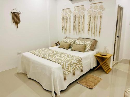 a white bedroom with a large bed and a table at La Palapa Inn Port Barton in San Vicente