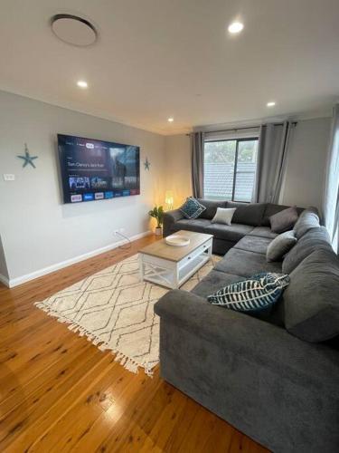 a living room with a couch and a flat screen tv at Bayview at Callala in Callala Bay