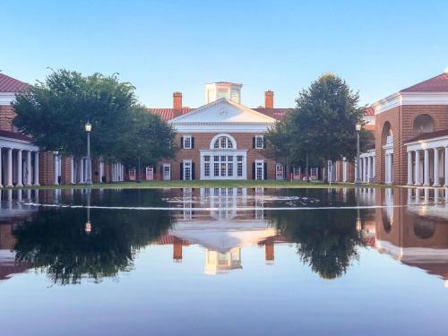 a large brick building with a reflection in the water at Kimpton - The Forum Hotel by IHG in Charlottesville