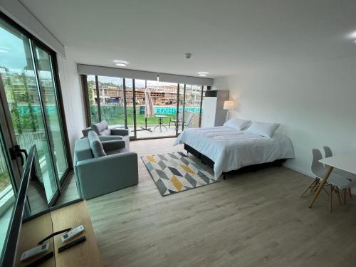 a bedroom with a bed and a couch and a table at SYRAH Premium B1 - Vistas al Parque by depptö in Punta del Este