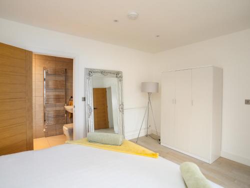 a white bedroom with a bed and a mirror at Bryn Min Manton Bach in Caernarfon
