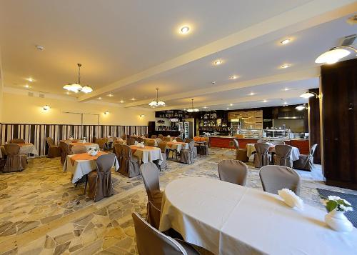 a restaurant with white tables and chairs and a kitchen at Hotel Ostrawa in Wodzisław Śląski
