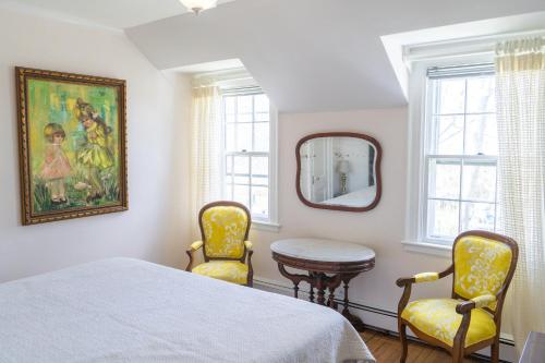 a bedroom with a bed and two chairs and a mirror at Rams Head Inn in Shelter Island