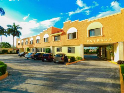 Hotel y Villas Costa del Sol في ميريدا: مبنى فيه سيارات متوقفة في موقف للسيارات