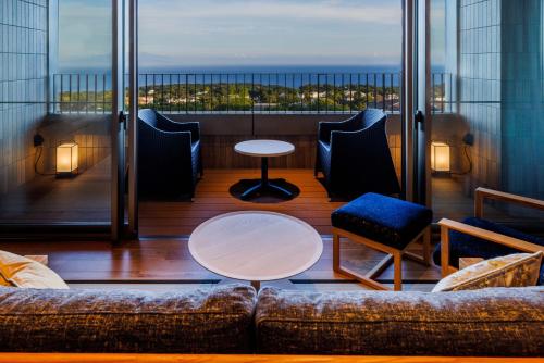 a living room with a couch and chairs on a balcony at KAMENOI HOTEL Izukogen in Ito