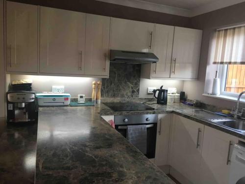 a kitchen with white cabinets and a granite counter top at 1 bedroom apartment with parking. in Great Wakering