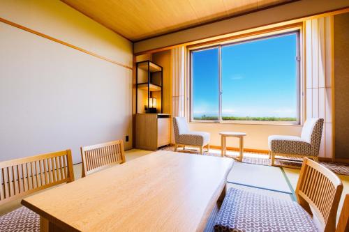 a room with a table and chairs and a large window at KAMENOI HOTEL Izukogen in Ito