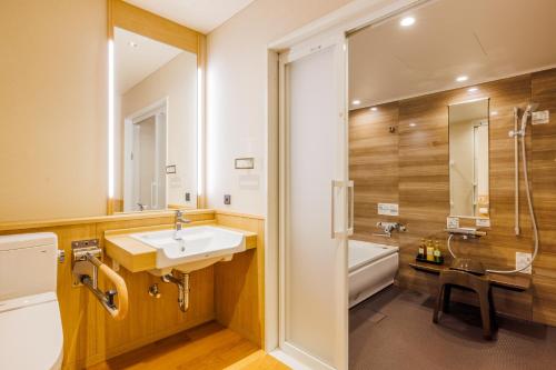 a bathroom with a sink and a toilet and a tub at KAMENOI HOTEL Izukogen in Ito