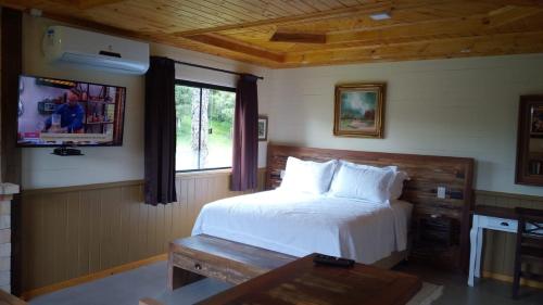 1 dormitorio con cama blanca y ventana en Pousada Trinca Ferro, en Bom Retiro
