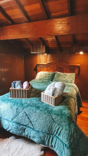 a bed with two baskets on top of it at Cabana Retrô com lareira e Ofurô em Monte Verde in Monte Verde