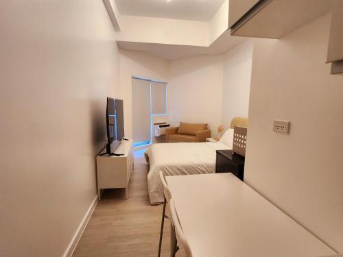 Cette petite chambre comprend deux lits et une télévision. dans l'établissement Minimalist Condo in Azure North, à San Fernando