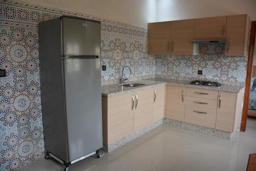 una cocina con nevera de acero inoxidable y armarios en Ozoud high standing appartment, en Ouzoud