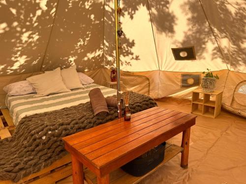 1 dormitorio con 1 cama en una tienda con mesa de madera en GLAMPING RANCHO ALEGRE en Merlo