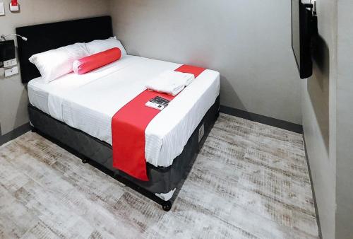 a bedroom with a bed with red and white sheets at Central District Hotel Davao in Davao City