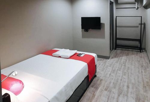a small room with a bed and a flat screen tv at Central District Hotel Davao in Davao City
