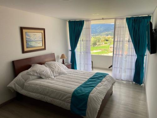 een slaapkamer met een bed en een groot raam bij RUSTICO 709 in Paipa