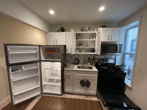 uma cozinha com armários brancos e um frigorífico aberto em New Apartament one Single Ride from Manhattan.. em Long Island City