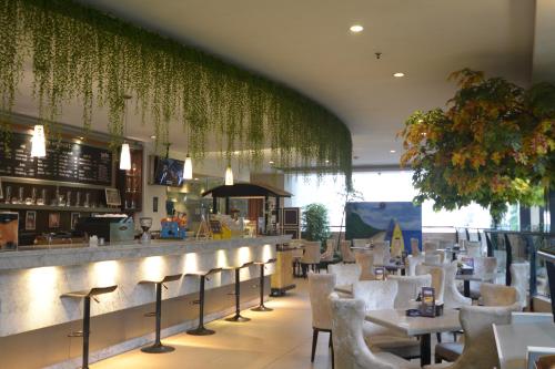 um restaurante com cadeiras brancas e um bar com plantas em Grand Savero Hotel Bogor em Bogor