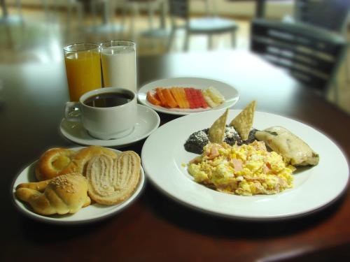 a table with two plates of breakfast foods and a cup of coffee at Hotel La Venta Inn Villahermosa in Villahermosa