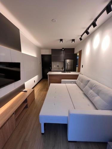 sala de estar con sofá blanco y cocina en Loft Barra norte, en Balneário Camboriú