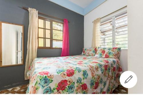 um quarto com uma cama com colcha floral em Cabaña Vistas del Bosque piscina privada em Jarabacoa