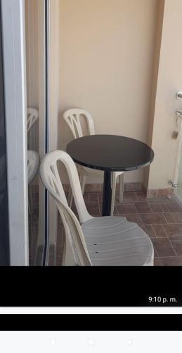 une table et quatre chaises blanches autour d'une table noire dans l'établissement Posada San pedro, à Tinjacá