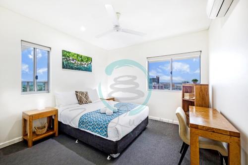 a bedroom with a bed and a desk and windows at ZEN BY THE WATER - Darwin's Premier Ocean View Family Retreat in Darwin