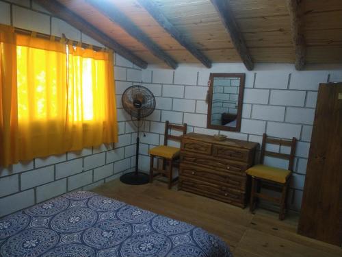 a bedroom with a fan and a dresser and chairs at Cabañas Rio y Playa in Atos Pampa