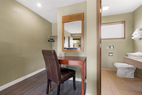 a bathroom with a desk with a chair and a toilet at Safari Inn - Chico in Chico