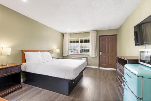 Habitación de hotel con cama y TV en Safari Inn - Chico, en Chico