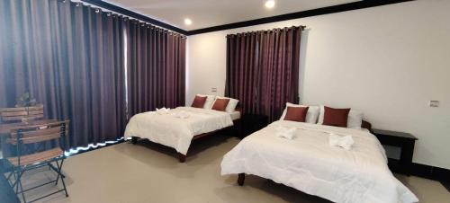 a bedroom with two beds and a window with curtains at Paradise Cozy Guesthouse Sihanoukville in Sihanoukville